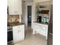 Bright eat-in kitchen with white cabinets, open shelving, and stainless steel appliances creating a cozy atmosphere at 6603 Adams St, New Port Richey, FL 34652