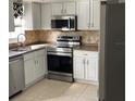Beautiful updated kitchen with stainless steel appliances, bright white cabinets, and neutral counters at 6603 Adams St, New Port Richey, FL 34652