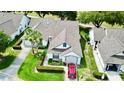 Aerial view of a well-maintained home with mature landscaping and a red car in the driveway at 9200 Turnberry Ct, New Port Richey, FL 34655