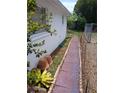 Landscaped backyard featuring a brick pathway, greenery, and fenced area adding charm to the property at 9516 Glen Moor Ln, Port Richey, FL 34668