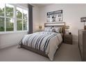 Tastefully decorated bedroom featuring stylish decor and a large window with a view to a leafy backyard at 9533 Vibrant Ln, Venice, FL 34292