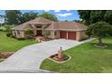 Exterior view of home featuring a brick facade, a two-car garage, and well-maintained lawn at 10044 Twelve Oaks Ct, Weeki Wachee, FL 34613