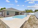 Backyard featuring a pool and jacuzzi, with a view of the house and lush vegetation around the fence at 10120 Ives Loop, Hudson, FL 34667