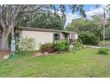 Exterior showcasing the house with a wooden ramp, mature trees, and a well-maintained lawn at 10149 Huntley St, New Port Richey, FL 34654