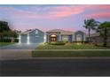 Charming single-story home with a well-manicured lawn, red front door, and attached two-car garage at dusk at 10250 Locker Dr, Spring Hill, FL 34608