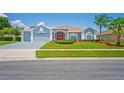 Charming single-story home with a well-manicured lawn, red front door, and attached two-car garage at 10250 Locker Dr, Spring Hill, FL 34608