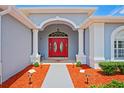 Home's front entrance featuring a bright red double door, decorative columns, and well-lit walkway at 10250 Locker Dr, Spring Hill, FL 34608