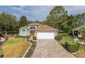 Charming single-story home featuring a well-manicured lawn and a brick paver driveway at 11404 Inman Ct, Spring Hill, FL 34609