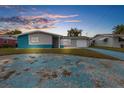 Charming single-story home with a blue driveway and unique architectural details at sunset at 12535 Third Isle, Hudson, FL 34667