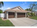 Single-story home with a two-car garage, showcasing a well-maintained lawn and landscaping and a white fence at 1862 Wood Bend St, Tarpon Springs, FL 34689