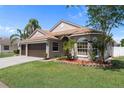 Charming single-story home with a well-manicured lawn, mature landscaping, and a two-car garage on a sunny day at 1862 Wood Bend St, Tarpon Springs, FL 34689
