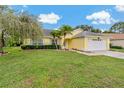 View of the front yard and yellow exterior of the home with an attached two-car garage at 4125 Mc Clung Dr, New Port Richey, FL 34653