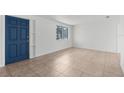 Bright and spacious living room featuring tile floors, a large window, and a vibrant blue front door at 6633 Jackson St, New Port Richey, FL 34653