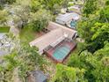 Aerial view of a private screened-in pool surrounded by lush greenery and mature trees at 7119 Lenape Cir, New Port Richey, FL 34653