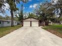 A long driveway leads to a charming house with a two-car garage and mature trees at 7119 Lenape Cir, New Port Richey, FL 34653