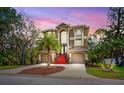 Stunning two-story home with a palm tree in the front yard at dusk offering great curb appeal at 7340 Brightwaters Ct, New Port Richey, FL 34652