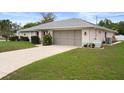 Single story home showcasing the two car garage and lush green lawn and manicured shrubs at 8283 Shoup St, Spring Hill, FL 34606