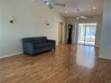 Open living room featuring hardwood floors, ceiling fans, and sliding glass doors to enclosed patio at 8291 Weeping Willow St, Brooksville, FL 34613
