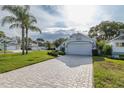 A bright single-Gathering home featuring manicured landscaping, a long brick driveway, and a two-car garage at 1084 Vista Fina Ct, Spring Hill, FL 34608