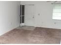 Neutral carpeted living room, featuring a screen door, bright natural light from the window, and simple design at 11715 Boynton Ln # 74B, New Port Richey, FL 34654