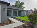 Welcoming front entrance featuring a landscaped walkway leading to a stylishly designed home at 12064 Cradock St, Spring Hill, FL 34608