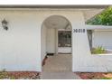 Inviting front porch with textured tile, archway, and decorative lighting at 16018 Adobe Dr, Hudson, FL 34667