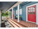 Inviting front porch with wood floors, red doors, white columns, offering a charming entrance to the home at 1602 Beachway Ln, Odessa, FL 33556