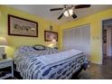 This bright bedroom has a full closet, decorative wall art, and neutral flooring with an overhead ceiling fan at 1934 Golfview Dr # 1934, Tarpon Springs, FL 34689