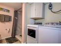Bathroom features a washer and dryer, shower with marble-style walls, and a storage cabinet for convenience at 1934 Golfview Dr # 1934, Tarpon Springs, FL 34689