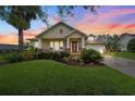 Charming single-story home at sunset featuring a well-manicured lawn, covered porch, and lush landscaping at 19531 Mossy Oak Ct, Brooksville, FL 34601