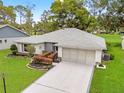 Aerial view showcasing the home's gray roof, landscaped yard, and extended driveway at 2310 Augusta Dr, Spring Hill, FL 34606