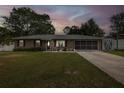 Charming single-story brick home at dusk with well-maintained lawn and covered garage at 27263 Warner Ave, Brooksville, FL 34602