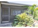 A covered front porch featuring tile floors and lush tropical landscaping around the entrance at 3140 Jackson Dr, Holiday, FL 34691