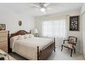 Cozy bedroom featuring a wooden bed frame, soft lighting, ceiling fan, and sheer curtains at 3832 Sailmaker Ln # 3832, Holiday, FL 34691