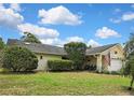 Wide view of a charming single-story home featuring a well-manicured lawn, lush landscaping, and a side entry garage at 4072 Everett Ave, Spring Hill, FL 34609