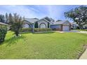 Attractive single-story home featuring mature landscaping, arched windows, and a two-car garage at 5249 Wellfield Rd, New Port Richey, FL 34655