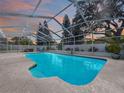 Screen enclosed pool with lounge chairs and lush landscaping under blue sky at 5249 Wellfield Rd, New Port Richey, FL 34655