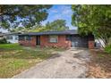 A charming single-story home with brick accents, dark trim, an attached garage, and a concrete driveway at 5323 23Rd St, Zephyrhills, FL 33542