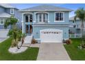 Two-story blue home with a two-car garage, balcony, manicured lawn, and lush landscaping at 6140 Seaside Dr, New Port Richey, FL 34652