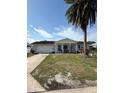 Single-story home with attached garage, green lawn, and mature palm tree in the front yard at 7540 Briarwood Dr, Port Richey, FL 34668