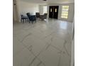 Spacious living room featuring bright white tile floors and abundant natural light from the double door entryway at 7540 Briarwood Dr, Port Richey, FL 34668