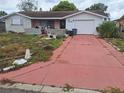 Exterior view of a one-story home with a long driveway and attached garage at 7631 Briarwood Dr, Port Richey, FL 34668