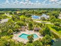 Aerial view of a community pool and surrounding amenities, set amongst lush landscaping and nearby pond at 8158 Sturbridge Ct # D, Weeki Wachee, FL 34613