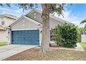 Charming one-story home featuring a blue garage door, well-maintained landscaping and a mature shade tree at 8335 Crescent Moon Dr, New Port Richey, FL 34655