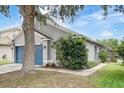 Charming single-story home featuring a blue garage door, gray stucco, and manicured landscaping at 8335 Crescent Moon Dr, New Port Richey, FL 34655