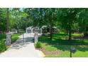Gated entrance to a beautiful home with lush green lawns, mature trees, and an inviting driveway at 8518 Quail Hollow Blvd, Wesley Chapel, FL 33544