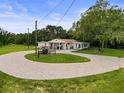 An aerial view of the property featuring a circular driveway and a white home surrounded by lush greenery at 8540 Roseanne Blvd, New Port Richey, FL 34654
