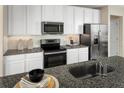 Modern kitchen with white cabinets, granite countertops, and stainless steel appliances at 8921 Waxwing Way, Parrish, FL 34219