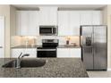 Bright kitchen featuring stainless steel appliances, granite counters, and white cabinetry at 8921 Waxwing Way, Parrish, FL 34219