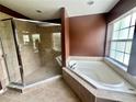 Bathroom featuring a garden tub, glass enclosed shower, and earth tone colors at 930 Woodbridge Ct, Safety Harbor, FL 34695